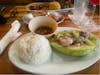 My plate is white rice with red beans and octopus on top of a avocado ( highly recommended ) if zoom the picture the other plate is a gigantic pork chop with yellow rice and beans . In the middle plate is little empanadas for appetizers 