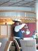 A waiter up in the buffet serving coffee with the tray on his head