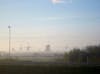 Early morning view of windmills in mist.