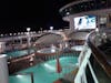 Watching a movie on a giant screen t.v by the pool at night 